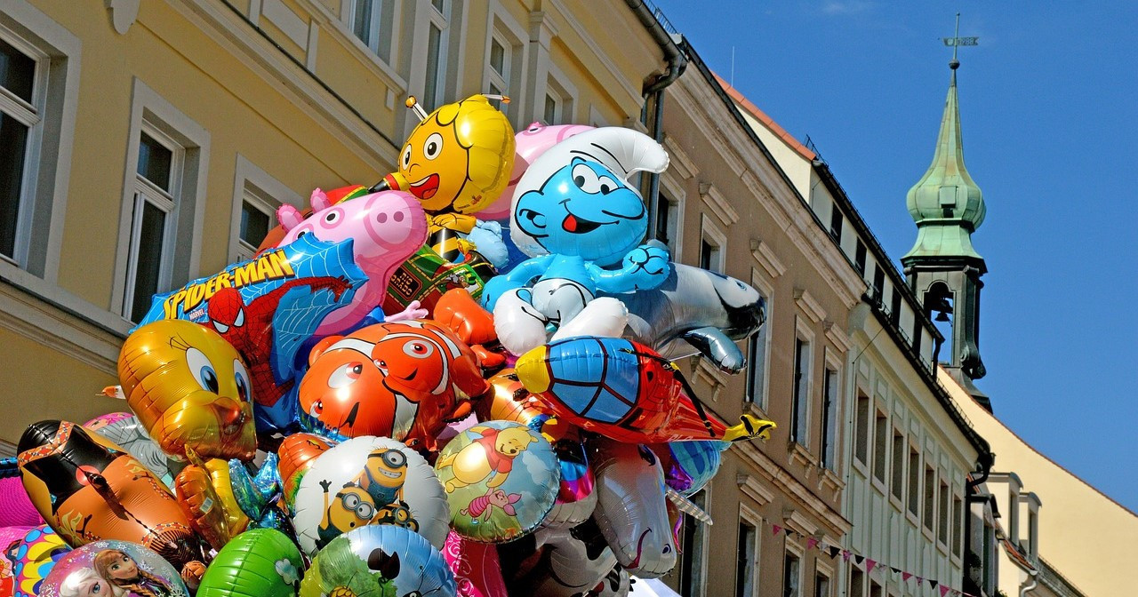 Große Menge bunter Luftballons in historischer Altstadt.