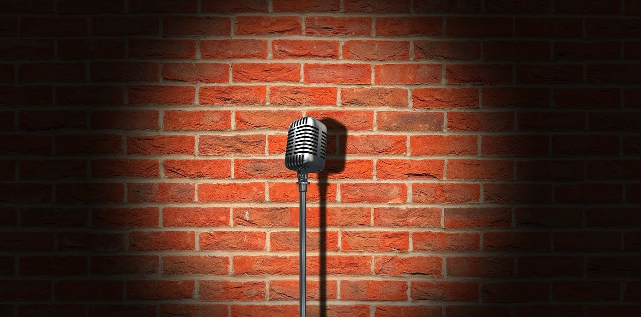 Mikrofon im Ständer auf Bühne vor gemauerter Steinwand.