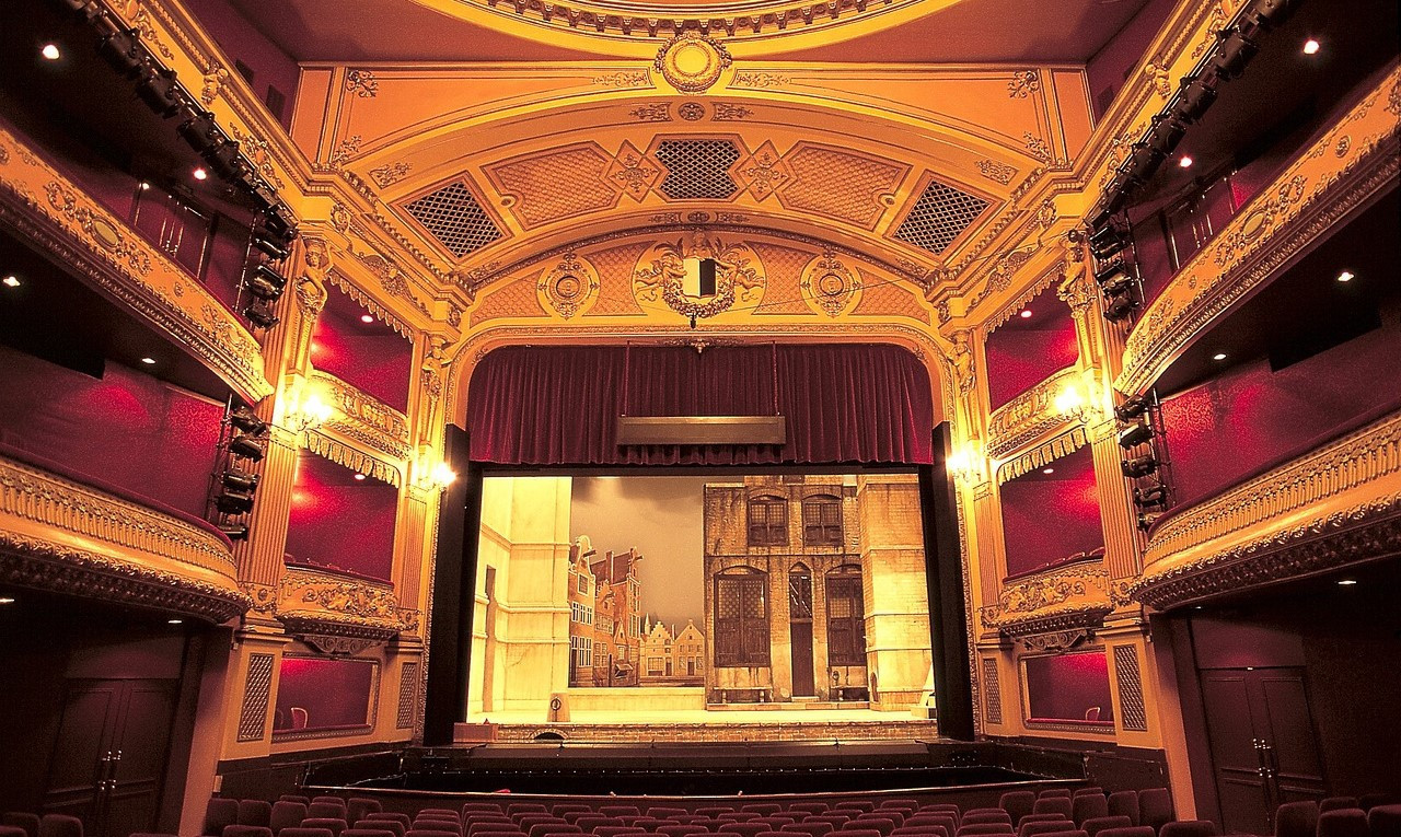 Ein leerer Opernsaal in goldenem Licht mit Blick auf die Bühne.