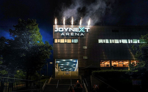Joynext-Arena: Der Schriftzug ist brandneu. Die Sportsbar empfängt im ersten Obergeschoss, wo es orange durch die Fenster leuchtet.