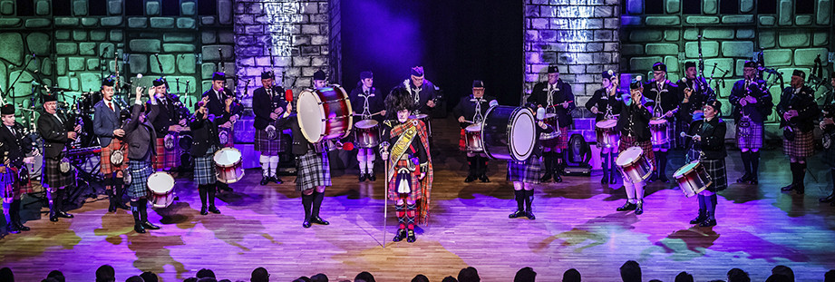 Musikgruppe in schottischen Trachten mit traditionellen Instrumenten auf Bühne.